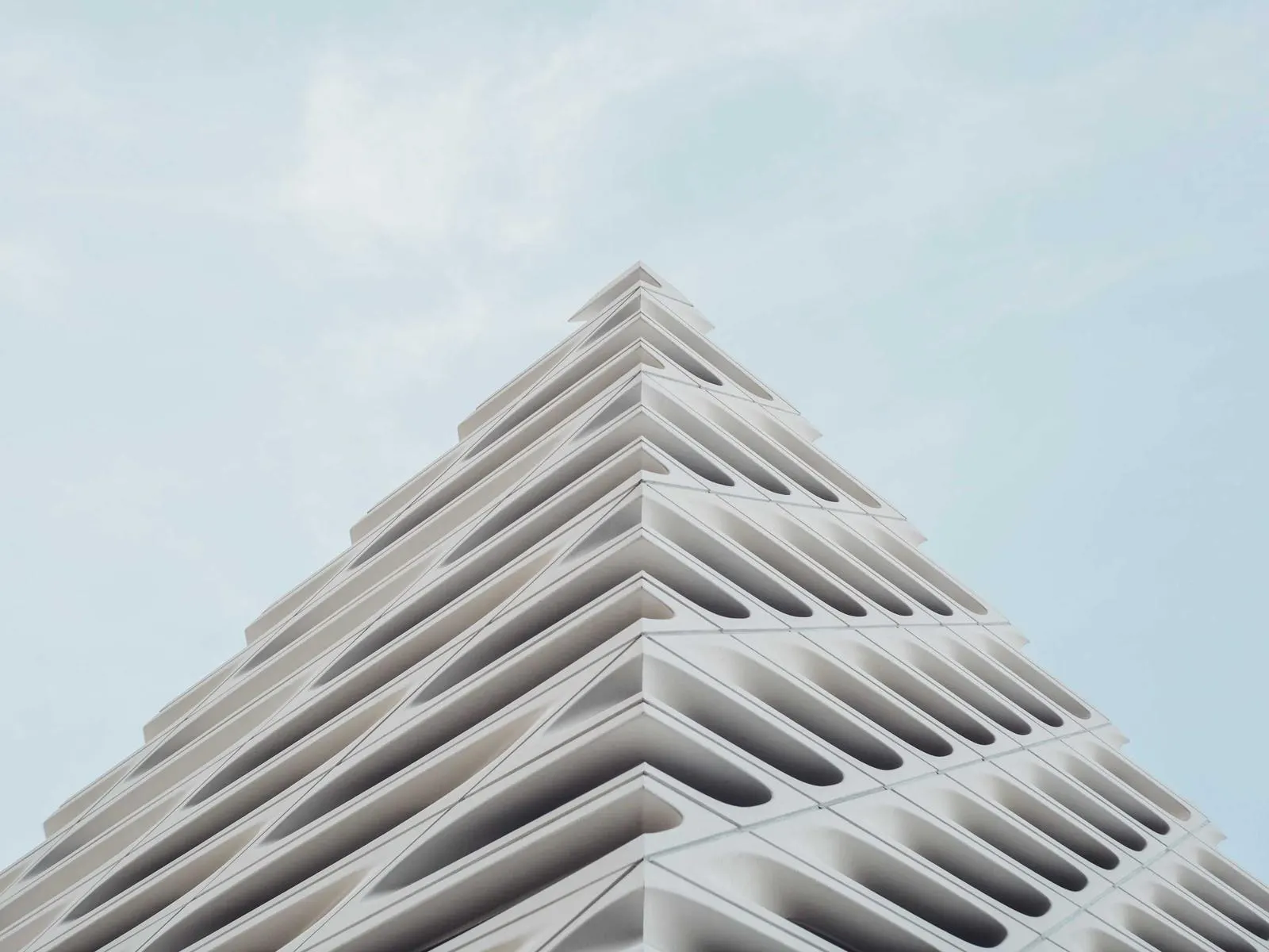 White sculptural facade of a modern building against a pale sky